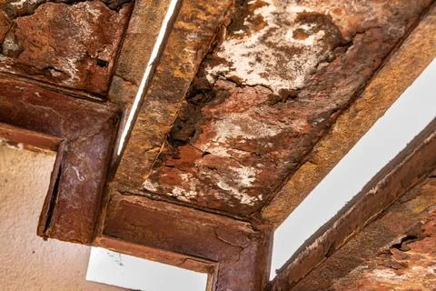 Corroded metal support frame under a porch, with visible decay and loss of Stock Photos