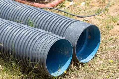 Corrugated plastic pipes lying on construction site ground Stock Photos