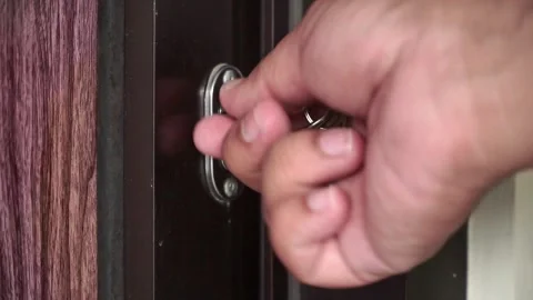 Cose-up shot of a hand grabbing a key from a door lock and opening a wooden Stock Footage 323036032
