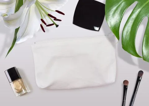 Cosmetic bag mock-up surrounded by make-up stuff and tropical plants Stock Photos