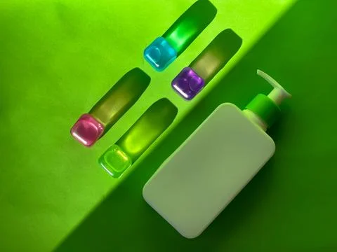 Cosmetic bottle and multicoloured translucent cubes. Sunlight and shadows Stock Photos