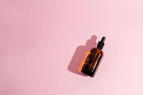 Cosmetic bottle on pink background, isolate, minimalism. Cosmetology, treatment. Stock Photos