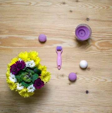 Cosmetic flat lay with roller, bombs, candle and flowers on wooden background Stock Photos