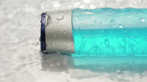 Cosmetic plastic bottle in splashes and drops of water. Skin care product, blue Stock Footage 164102466