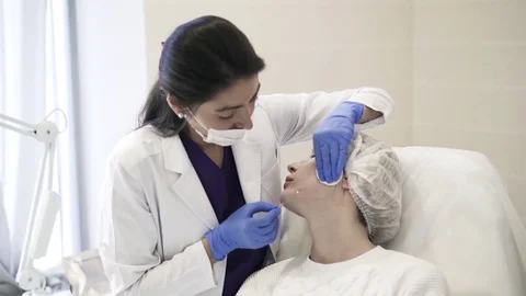 Cosmetician inserting needle into cheek 스톡 동영상 75693594