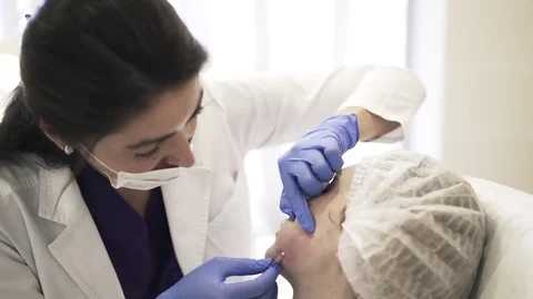 Cosmetician inserting needle into cheek, side view 스톡 동영상 75693732