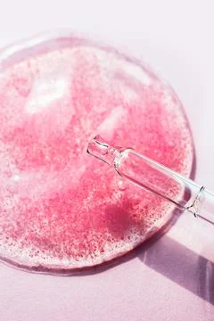 Cosmetics drop macro on pink background. Beauty serum gel laboratory test Stock Photos