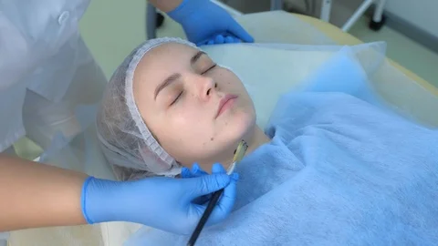 Cosmetologist applying carbon nanogel to skin of woman's face using brush. Video stock 124952753