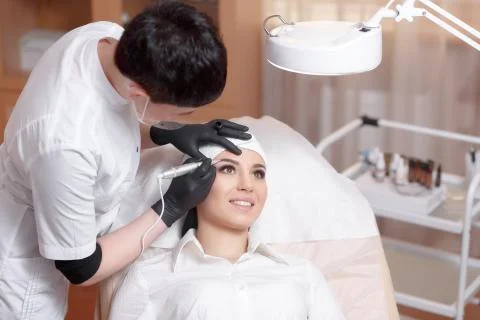 Cosmetologist applying permanent make up on eyebrows- eyebrow tattoo Stock Photos