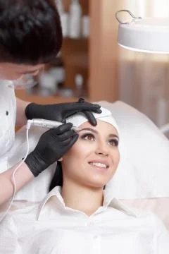 Cosmetologist applying permanent make up on eyebrows- eyebrow tattoo Stock Photos