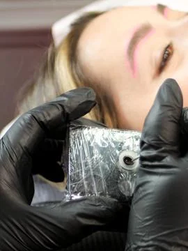 Cosmetologist applying permanent make up eyebrows for a client in a salon Stock Photos