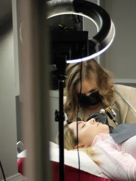 Cosmetologist applying permanent make up eyebrows for a client in a salon Stock Photos