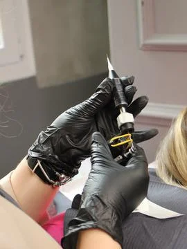 Cosmetologist applying permanent make up eyebrows for a client in a salon Stock Photos