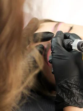 Cosmetologist applying permanent make up eyebrows for a client in a salon Stock Photos