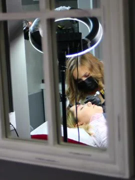 Cosmetologist applying permanent make up eyebrows for a client in a salon Stock Photos