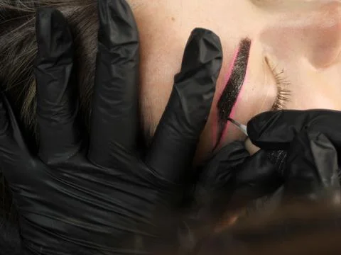 Cosmetologist applying permanent make up eyebrows for a client in a salon Stock Photos