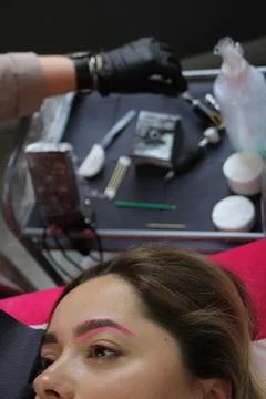 Cosmetologist applying permanent make up eyebrows for a client in a salon Stock Photos
