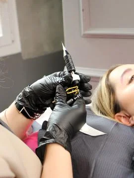 Cosmetologist applying permanent make up eyebrows for a client in a salon Stock Photos