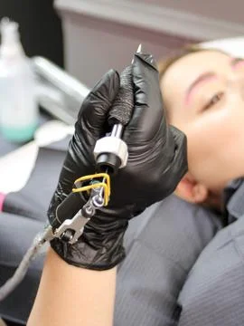 Cosmetologist applying permanent make up eyebrows for a client in a salon Stock Photos