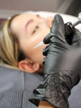 Cosmetologist applying permanent make up eyebrows for a client in a salon Stock Photos