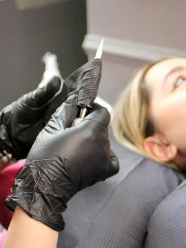 Cosmetologist applying permanent make up eyebrows for a client in a salon Stock Photos