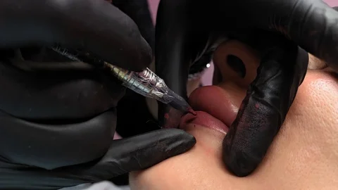 Cosmetologist applying permanent makeup on lips. Cosmetology procedure. Applying Video stock 119892242