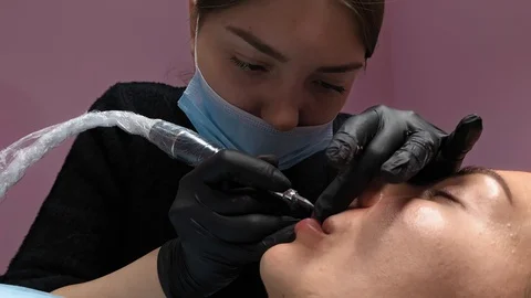 Cosmetologist applying permanent makeup on lips. Cosmetology procedure. Applying Video stock 119892378