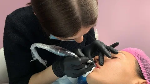 Cosmetologist applying permanent makeup on lips. Cosmetology procedure. Applying Video stock 119892559
