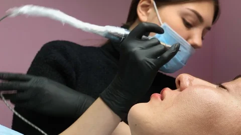 Cosmetologist applying permanent makeup on lips. Cosmetology procedure. Applying Video stock 119892641