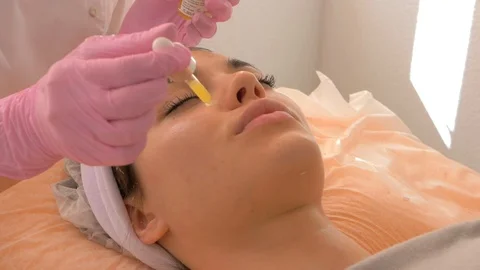 Cosmetologist is applying serum on the face of the model. Video stock 118920525