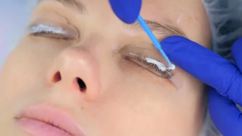 Cosmetologist is applying solution for lamination on lashes, lifting procedure. Video stock 136873511