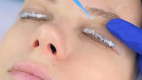 Cosmetologist is applying solution for lamination on lashes, lifting procedure. Video stock 136874114