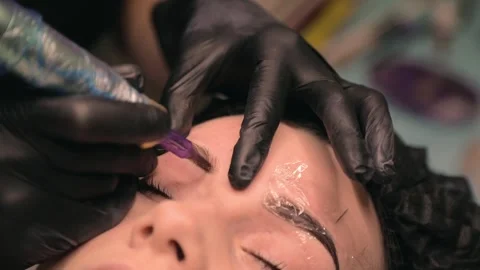 The cosmetologist creates neat eyebrows using permanent makeup. Stock Footage 290204779