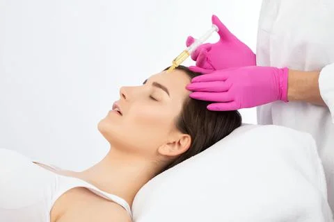 Cosmetologist does prp therapy on the face of a beautiful woman in a beauty s Stock Photos