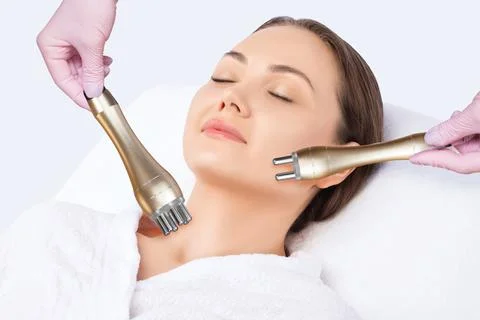 The cosmetologist does rf-lifting of the face skin of a beautiful woman in a  Stock Photos