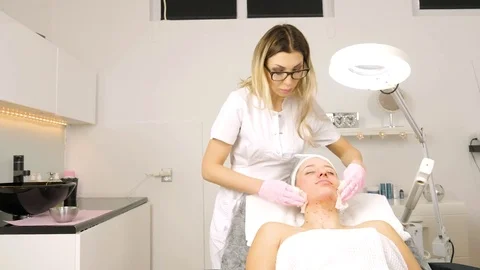 Cosmetologist is doing Face peeling mask, spa beauty treatment for young girl. Stock Footage 84179329