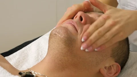 Cosmetologist is doing procedure of face massage for young boy / man. Stock Footage 84179611