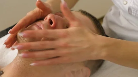 Cosmetologist is doing procedure of face massage for young boy / man. Stock Footage 84179793
