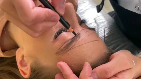 Cosmetologist drawing right shape of eyebrows during permanent makeup process Stock Footage 200482303