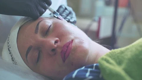 Cosmetologist in gloves making face injection in a female skin Stock Footage 95984038