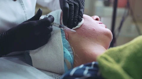 Cosmetologist in gloves making face injection in a female skin Stock Footage 95984064