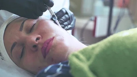 Cosmetologist in gloves making face injection in a female skin Stock Footage 95984089