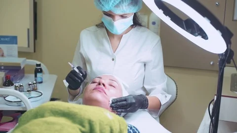 Cosmetologist in gloves making face injection in a female skin Stock Footage 95984120