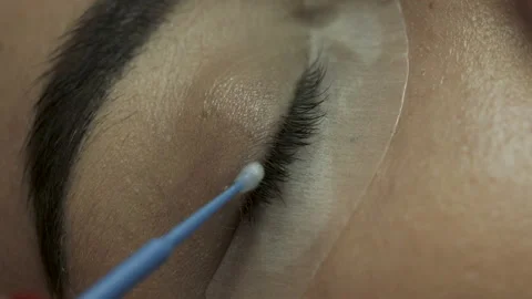 Cosmetologist lubricating old eyelashes with a solution to remove. Macro eyelash Stock Footage 106957005