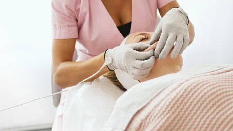 Cosmetologist makes a procedure on the cheekbones with microcurrent Stock Footage 236026143