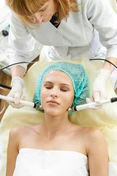 Cosmetologist makes the procedure microcurrent therapy beauty salon Stock Photos