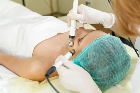 Cosmetologist makes the procedure microcurrent therapy beauty salon Stock Photos