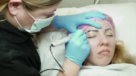 Cosmetologist is making an eyebrow permanent makeup in salon Stock Footage 74215012