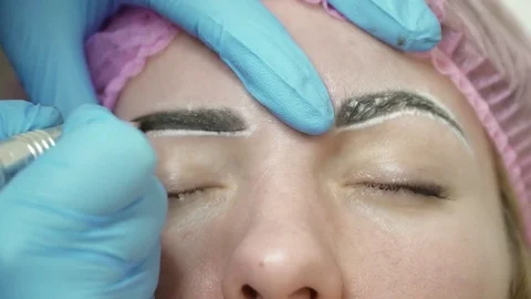 Cosmetologist is making an eyebrow permanent makeup in salon closeup Stock Footage 74215064