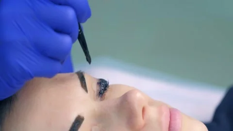 Cosmetologist making lash laminating, eyebrow and lash painting for woman. Stock Footage 136874598